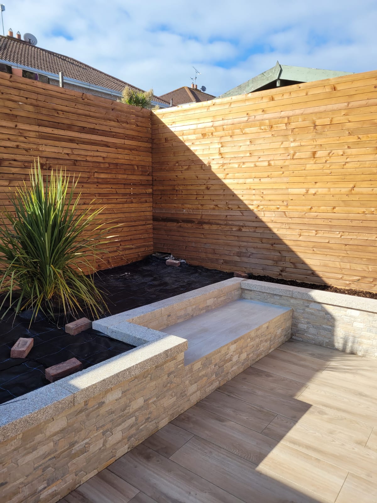 Garden design with wooden effect patio and custom flower beds